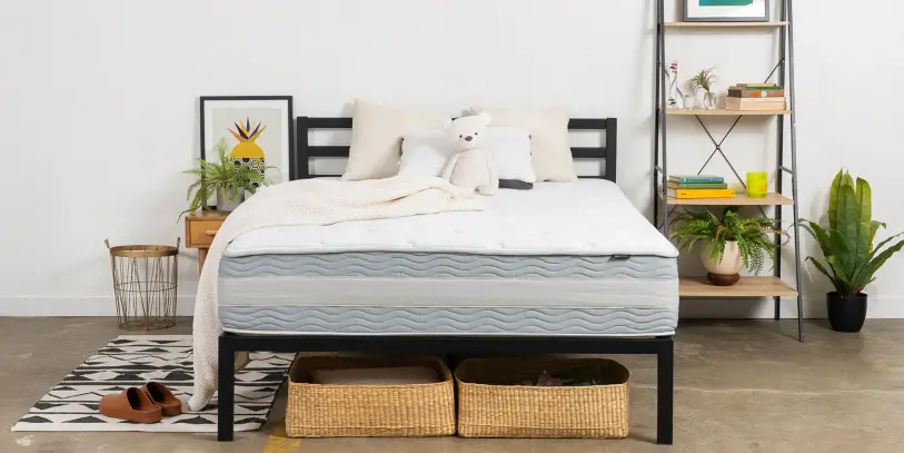 A mattress on a wooden bed frame in a sunlit bedroom