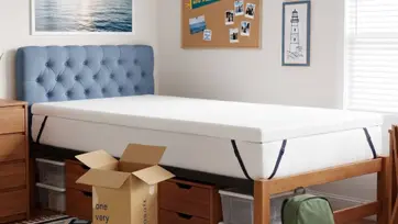 young man moving into collage putting mattress topper on his bed